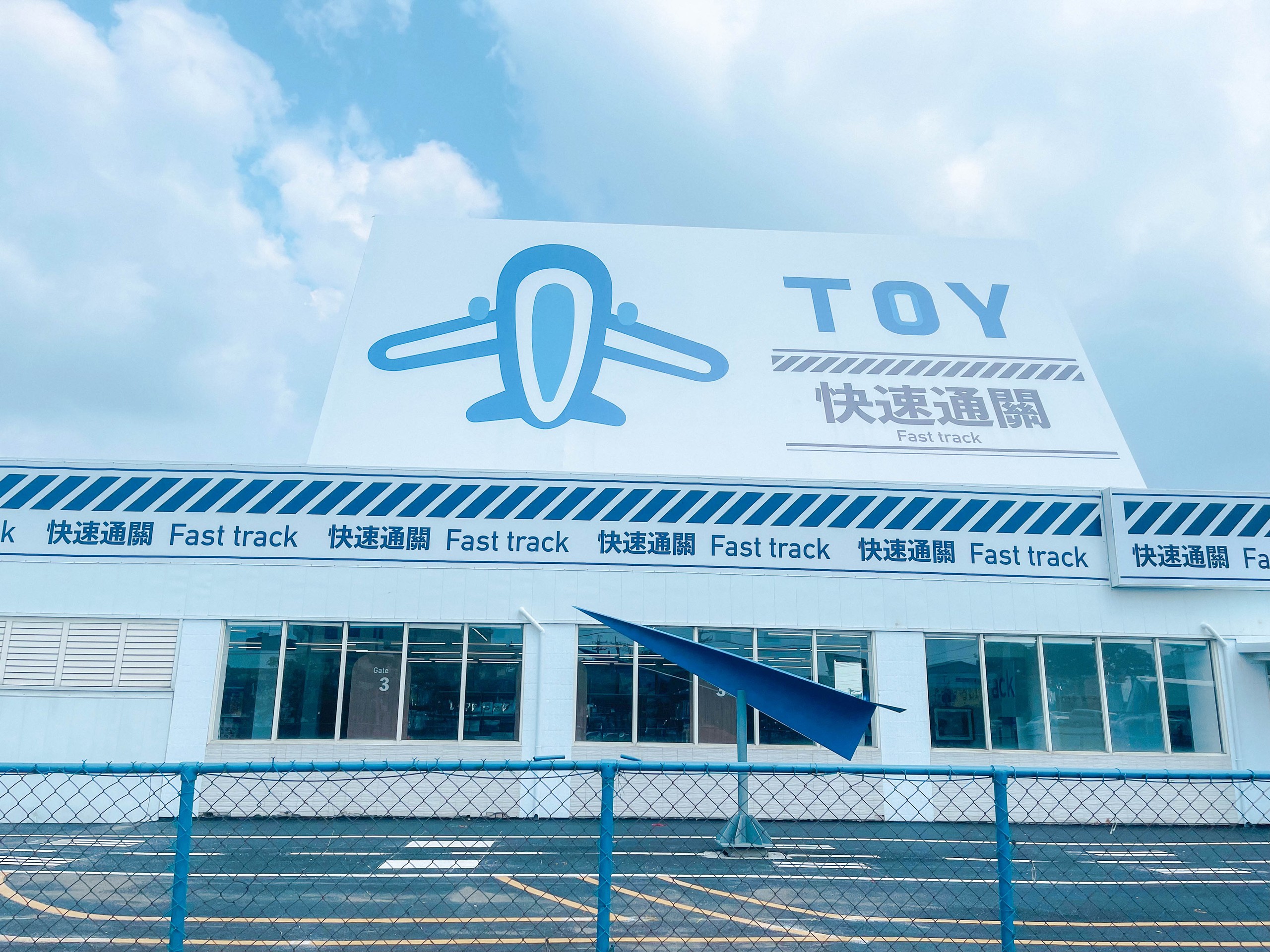 快速通關玩具店結帳區:藍色塑膠籃排在伸縮式滾輪輸送帶上,仿行李輸送帶,大面開窗引入自然光,動線清晰